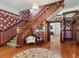 Ornate and stunning foyer with custom wallpaper, seating area with bookshelves and multiple coat closets.