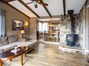 Main home living room with exposed beams and wood burning stove